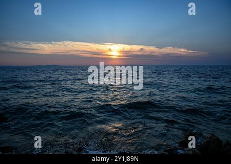 Le soleil se couche sur l'océan, projetant une lueur chaude sur l'eau. Banque D'Images