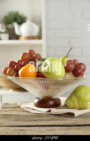 Vase en verre avec différents fruits frais sur une table en bois Banque D'Images