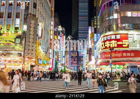 Tokyo, Japon, 16 juin 2024 : les gens traversent les intersections les plus populaires à Shinjuku avec le monument Godzilla Head et l'attraction touristique à Banque D'Images