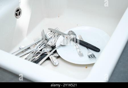 Gros plan de l'évier de cuisine en céramique blanc plein de vaisselle sale non lavée Banque D'Images