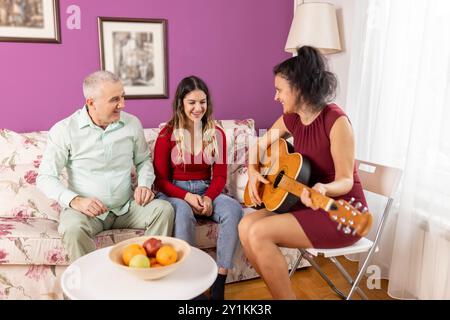 Cette famille aime passer les week-ends ensemble, et l'une de leurs activités préférées est de jouer de la guitare et de chanter. Tout le monde aime ce passe-temps partagé an Banque D'Images