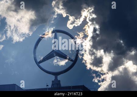 Image symbolique, nuages sombres chez Mercedes, logo Mercedes sur un bâtiment entouré de formations nuageuses spectaculaires et de rayons de lumière dans le ciel bleu, Stuttg Banque D'Images