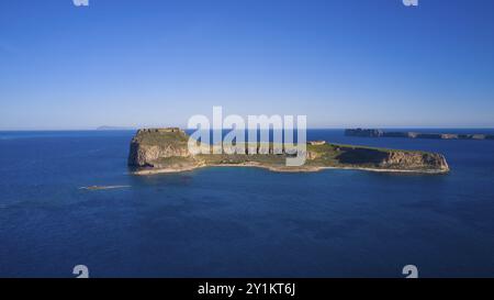 Drone shot, petite île isolée avec une côte rocheuse entourée par la large mer bleue sous un ciel clair, forteresse marine vénitienne, Gramvoussa, Gramvou Banque D'Images