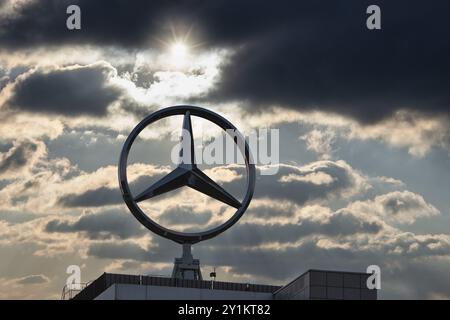 Image symbolique, nuages sombres chez Mercedes, logo Mercedes sur un bâtiment entouré de formations nuageuses spectaculaires et de rayons de lumière dans le ciel bleu, Stuttg Banque D'Images