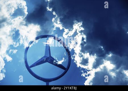 Image symbolique, nuages sombres chez Mercedes, logo Mercedes sur un bâtiment entouré de formations nuageuses spectaculaires et de rayons de lumière dans le ciel bleu, Stuttg Banque D'Images