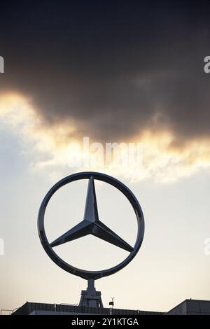 Image symbolique, nuages sombres chez Mercedes, logo Mercedes-Benz devant un ciel couchant avec des nuages au-dessus d'un bâtiment industriel, Stuttgart-Untertuerkheim Banque D'Images