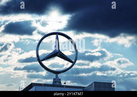 Image symbolique, nuages sombres chez Mercedes, logo Mercedes sur un bâtiment entouré de formations nuageuses spectaculaires et de rayons de lumière dans le ciel bleu, Stuttg Banque D'Images