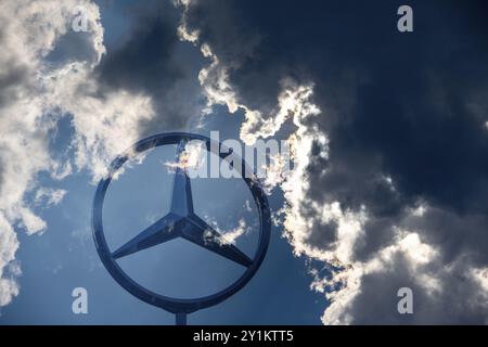 Image symbolique, nuages sombres chez Mercedes, logo Mercedes sur un bâtiment entouré de formations nuageuses spectaculaires et de rayons de lumière dans le ciel bleu, Stuttg Banque D'Images