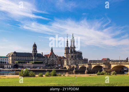 Dresdner Stadtbild Blick auf die Dresdner Altstadt mit der Katholischen Hofkirche auch bekannt als Kathedrale : Trinitatis und der Augustusbrücke. IM Vordergrund liegt eine Grüne Wiese entlang der Elbe. Die markante Barockarchitektur der Kirche und die Brücke prägen das Bild, während der Himmel klar und sonnig ist. Dresde Innere Neustadt Sachsen Deutschland *** paysage urbain de Dresde vue de la vieille ville de Dresde avec l'église de la cour catholique également connue sous le nom de cathédrale St Trinitatis et le pont Auguste au premier plan est une prairie verte le long de l'Elbe L'architecture baroque frappante de th Banque D'Images