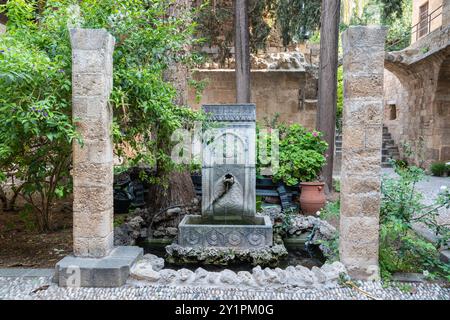 Rhodes Town, Grèce – 19 juillet 2024. Fontaine ancienne avec inscriptions arabes dans la cour du Musée archéologique de Rhodes dans la ville de Rhodes, Banque D'Images