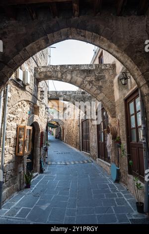 Ruelle étroite (rue Pythagore) avec des arches en pierre dans le quartier médiéval de Rhodes, Grèce. Banque D'Images