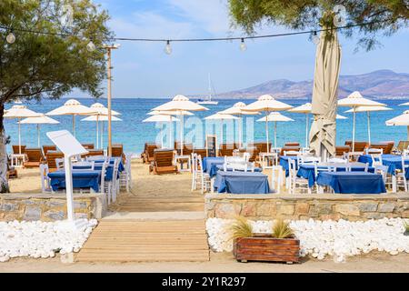 Tables et chaises derrière des chaises longues sur la plage d'Agios Prokopios, île de Naxos, Cyclades, Grèce Banque D'Images