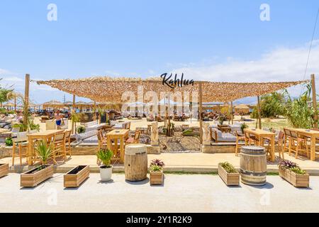 Tables et chaises derrière des chaises longues dans un bar de plage sur la plage d'Agios Prokopios, île de Naxos, Cyclades, Grèce Banque D'Images