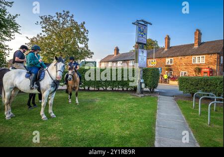 Les cavaliers apprécient un verre en selle au pub Hatton Arms dans la campagne de Stretton près de Warrington baigné par le soleil du soir. Banque D'Images