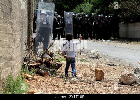 Un garçon palestinien lance des pierres sur des soldats israéliens lors d'une manifestation contre l'expansion des colonies juives dans le village de Kufr Qadoom, près de Naplouse, en Cisjordanie Banque D'Images