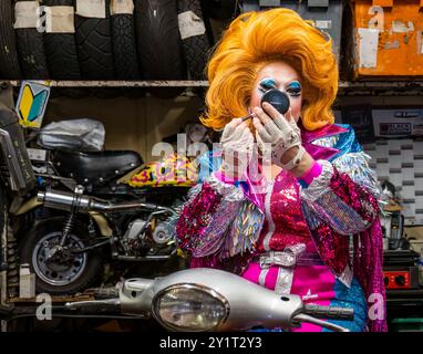 Drag Artist Ginger Johnson appliquant le maquillage sur une moto dans un atelier de réparation de motos à Edinburgh Festival Fringe, en Écosse, au Royaume-Uni Banque D'Images