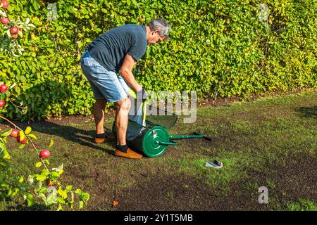 L'homme est vu charger la commode supérieure avec la terre du grand sac en plastique de restauration de pelouse dans le jardin résidentiel. Suède. Banque D'Images