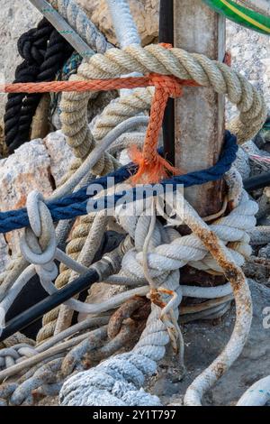 cordes enchevêtrées enroulées autour d'un poteau en bois, enchevêtrement de cordes et de cordages, enchevêtrement de cordes de navires, abstraction de cordes de différentes couleurs. Banque D'Images