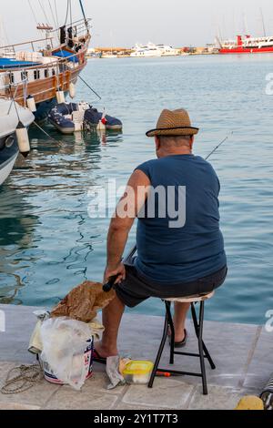 vieil homme retraité assis sur un quai de pêche dans le soleil méditerranéen chaud Banque D'Images