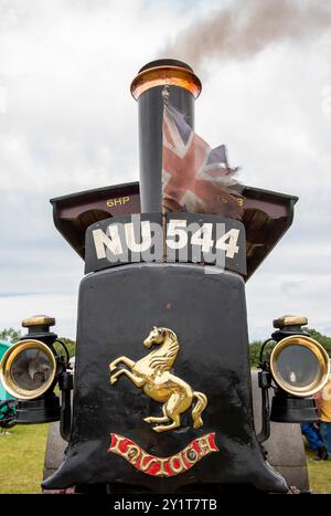 moteur de traction vintage ou rouleau à vapeur exposé à une foire à vapeur avec drapeau union jack en lambeaux volant de cheminée. rouleau à vapeur invicta. Banque D'Images