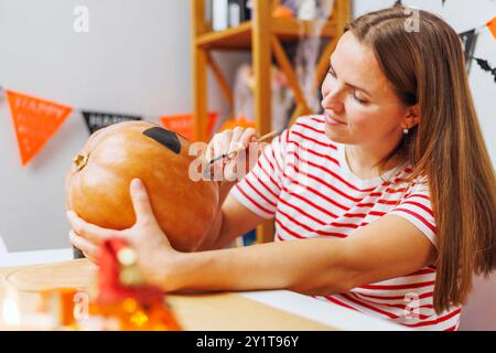 Femme peignant citrouille pour la décoration d'Halloween Banque D'Images