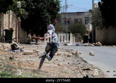 Un manifestant palestinien lance des pierres sur un véhicule militaire israélien lors d'affrontements à la suite d'une manifestation hebdomadaire contre l'expropriation de terres palestiniennes par Israël dans le village de Kfar Qaddum près de Naplouse, en Cisjordanie occupée. Banque D'Images