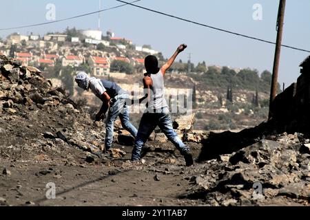 Un manifestant palestinien lance des pierres sur un véhicule militaire israélien lors d'affrontements à la suite d'une manifestation hebdomadaire contre l'expropriation de terres palestiniennes par Israël dans le village de Kfar Qaddum près de Naplouse, en Cisjordanie occupée. Banque D'Images