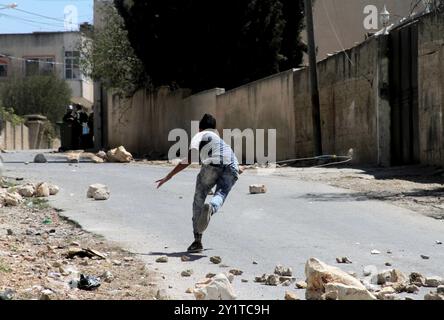 Un manifestant palestinien lance des pierres sur un véhicule militaire israélien lors d'affrontements à la suite d'une manifestation hebdomadaire contre l'expropriation de terres palestiniennes par Israël dans le village de Kfar Qaddum près de Naplouse, en Cisjordanie occupée. Banque D'Images