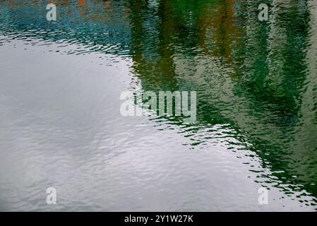 Image abstraite avec des ondulations sur l'eau et des reflets colorés des bâtiments. Banque D'Images