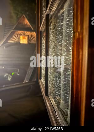 fenêtre ouverte dans un chalet en bois le soir pendant la pluie. Photo de haute qualité Banque D'Images