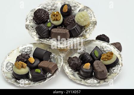 Différents types de pralines au chocolat sur plaques d'argent, gros plan, isolés sur fond blanc Banque D'Images