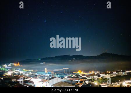 Une nuit d'hiver sereine à Villaviciosa de Cordoba, Andalousie, Espagne, avec du brouillard enveloppant la ville tranquille sous un ciel étoilé. Banque D'Images