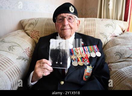 Photo du dossier datée du 03/06/19 de Don Sheppard, tenant une photo de lui-même jeune homme et portant ses médailles de campagne à sa maison de Basildon, Essex. Le vétéran du jour J qui a aidé à libérer le camp de concentration de Bergen-Belsen est décédé à l’âge de 104 ans. Sheppard, un pilote d'expédition pour les Royal Engineers, a atterri sur la plage Juno le 6 juin 1944 dans un char de navire de débarquement. Date d'émission : dimanche 8 septembre 2024. Banque D'Images