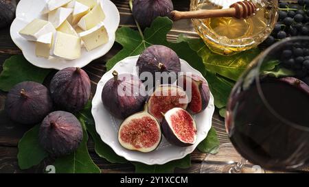 Plateau de fromage au camembert brie, figues biologiques juteuses saines, miel et raisins. Verre à vin rouge, ensemble d'apéritifs. Fruits de saison. Banque D'Images