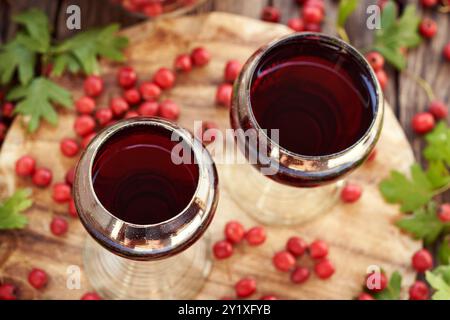 Deux tasses en verre de vin médicinal préparé à partir de baies d'aubépine fraîches sur une table Banque D'Images