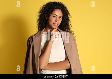 Belle femme avec veste élégante sur fond jaune Banque D'Images