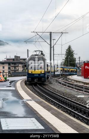 Grindelwald, Suisse - 22 juillet 2024 : le train arrive au quai de la gare de Grindelwald, jour de pluie couvert dans les alpes suisses Banque D'Images