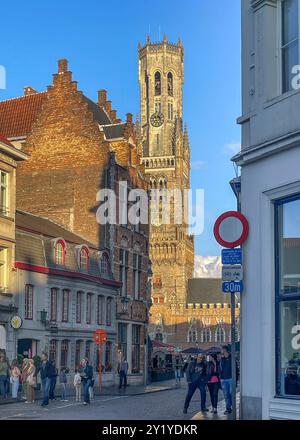 Bruges, Flandres, Belgique - 22 juin 2024 : Halletoren vu de Eiermarkt, coin geldmuntstraat avec des piétons sous la lumière du soir Banque D'Images