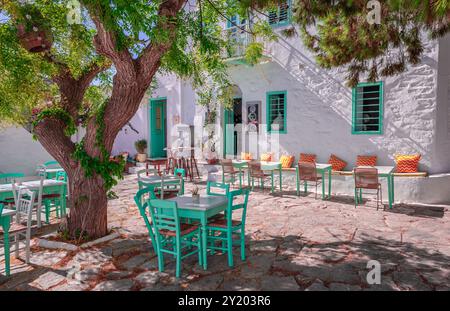 Chora d'Amorgos, Grèce - juillet 27 2024 : café en plein air sur la place de la capitale de l'île de la mer Égée. Maisons et tables blanchies à la chaux sous l'alose Banque D'Images