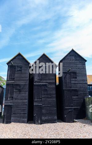 Trois hangars de séchage de filets de pêche noirs à Rock-a-Nore, Hastings par une journée ensoleillée avec un ciel bleu et des nuages blancs tortueux Banque D'Images