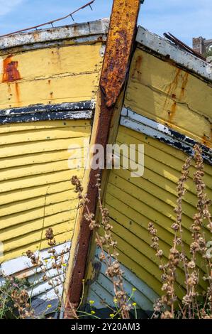 Vieux, jaune pâle, bateau de pêche en clinker en bois sur le rivage à Hastings, par une journée ensoleillée avec des raccords rouillés, à la proue Banque D'Images