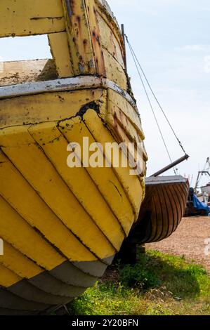 Vieux, jaune pâle, bateau de pêche en clinker en bois sur le rivage à Hastings, par une journée ensoleillée avec des raccords rouillés, à la poupe Banque D'Images