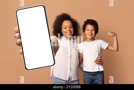 Mère et fils posant joyeusement avec un smartphone dans un cadre cosy Banque D'Images