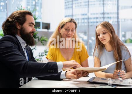 Gestionnaire de portefeuille en bureau analysant les rapports économiques, développant les objectifs de placement et discutant avec les clients. Conseiller financier aidant la famille qui veut acheter une maison Banque D'Images