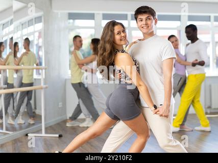 Heureux jeune femme et homme avec un groupe de danseurs internationaux formant la danse tango dans le cours de danse Banque D'Images