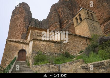 Église historique avec clocher et murs de pierre, situé au pied des montagnes escarpées, Las Penas de Riglos, comme Penyas de Riglos, Mallos de Riglos Banque D'Images