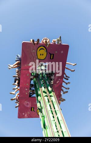 Les riders du parc d'attractions à la recherche de sensations fortes font l'expérience d'une tour de chute haute, vibrante, vue depuis un angle bas, ciel dégagé, concept amusant Banque D'Images