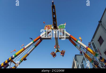 Tour d'attractions balançant coloré au parc avec des amateurs de sensations fortes contre le ciel bleu clair, tour de foire avec des gens s'amusant, divertissement tour de parc d'attractions concp Banque D'Images