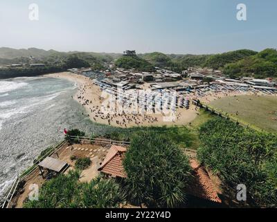 Vue aérienne de la plage de Drini à Gunungkidul, Yogyakarta, Indonésie avec des plages de sable blanc, des parasols, bondés de touristes. Banque D'Images