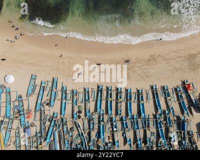 Vue de dessus de la plage de Drini à Gunungkidul, Yogyakarta, Indonésie avec de nombreux bateaux bleus sur le sable. Banque D'Images